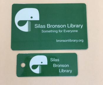Two green cards with "Silas Bronston Library" printed on them, highlighting the updated library card design.