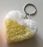 Pom pom key chain in the shape of a heart made of fluffy yarn.